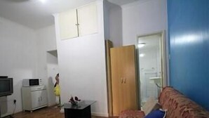Ett litet, kompakt bostadsutrymme med en soffa, en tv, en mikrovågsugn och ett skåp.