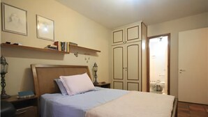 A bedroom with a bed, nightstands, a wardrobe, and a shelf with books. - GoHouse Dulcidio 307 (Rio de Janeiro)
