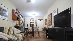 A living room with a black sofa, a television, and a bookshelf. - GoHouse Dulcidio 307 (Rio de Janeiro)