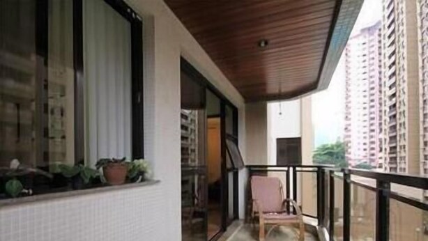 A balcony with a wooden table, a chair, and potted plants. - GoHouse Dulcidio 307 (Rio de Janeiro)
