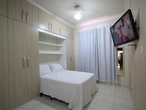 A bedroom with a bed, a TV mounted on the wall, and a wardrobe. - GoHouse Dutra 804 (Rio de Janeiro)