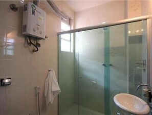 A bathroom with a glass shower enclosure, a white sink, and a towel rack. - GoHouse Dutra 804 (Rio de Janeiro)