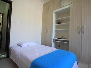 A bedroom with a bed, a wardrobe, and a small shelf unit. - GoHouse Dutra 804 (Rio de Janeiro)