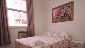 A bedroom with a bed, a nightstand, a dresser, and a window with curtains. - GoHouse Copacabana 901 (Rio de Janeiro)
