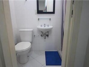 A small, clean bathroom with a toilet, sink, and mirror. - GoHouse Copacabana 901 (Rio de Janeiro)