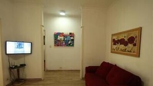 A living room with a red sofa, a television, and two paintings on the walls. - GoHouse Copacabana 901 (Rio de Janeiro)