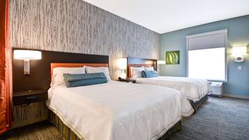 Une chambre d’hôtel avec deux lits, une tête de lit en bois, une grande fenêtre et un climatiseur fixé au mur.