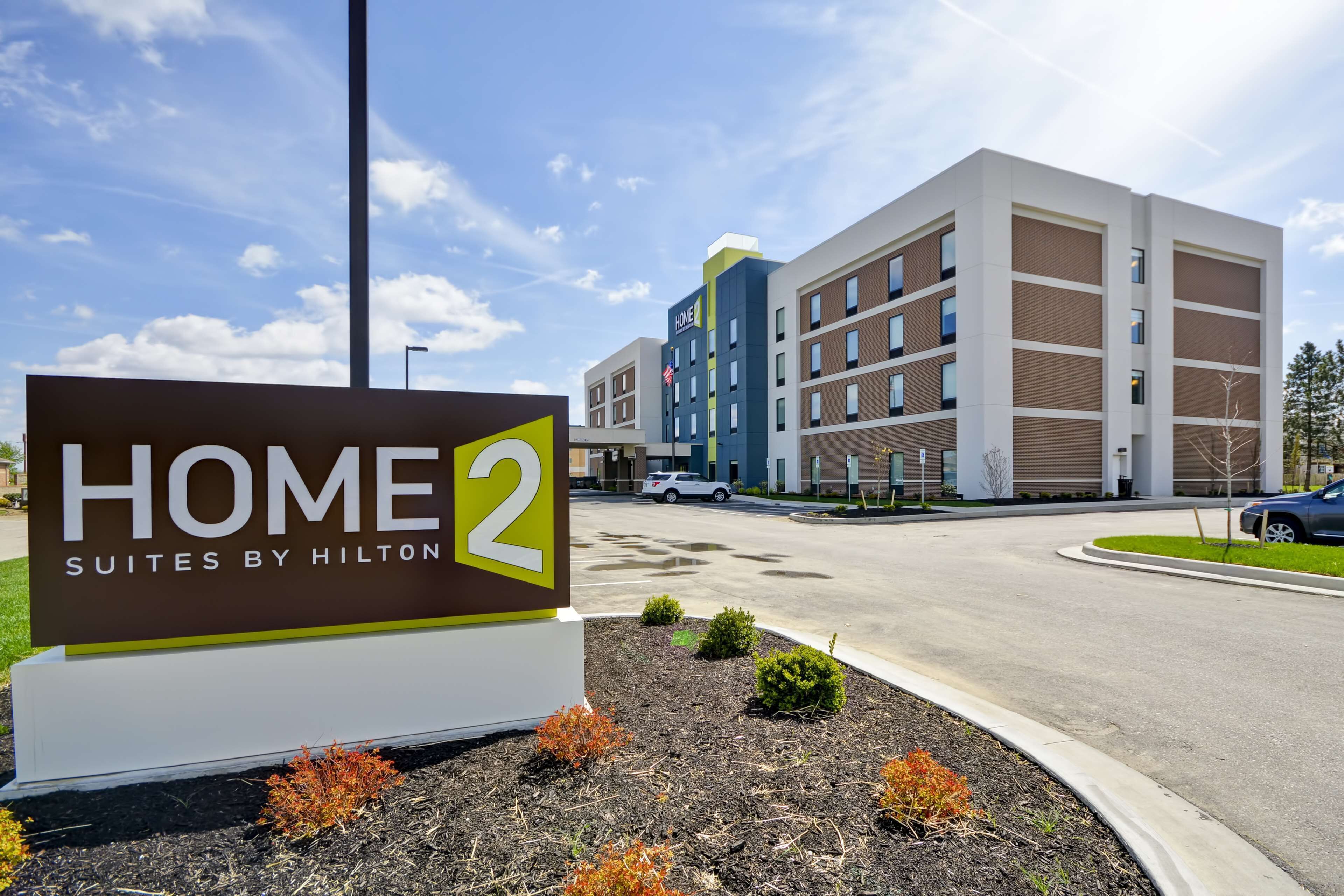 A sign for Home 2 Suites by Hilton, indicating a hotel with multiple floors and a modern design.