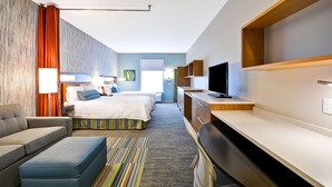 Una habitación de hotel moderna con cama, sofá, escritorio y televisión.
