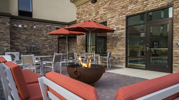 An outdoor patio with seating, a fire pit, and umbrellas. - Hampton Inn Decatur Mt. Zion (Decatur)