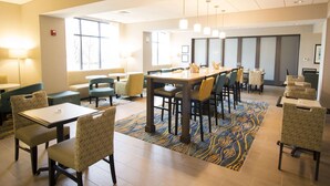 A spacious dining area with multiple tables and chairs, a patterned carpet, and large windows allowing natural light. - Hampton Inn Decatur Mt. Zion (Decatur)