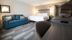A hotel room with a bed, a sofa, a desk, and a TV. - Hampton Inn Decatur Mt. Zion (Decatur)