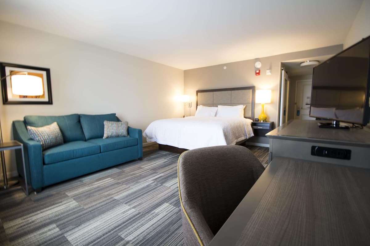 Een hotelkamer met een bed, een bank, een bureau en een televisie.