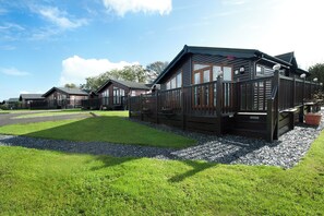 A row of cabins with a gravel pathway leading to them, surrounded by well-maintained grass. - Killigarth Manor Holiday Park (Looe)