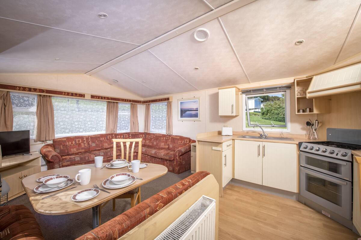 A compact RV interior with a dining area, kitchenette, and a living space.