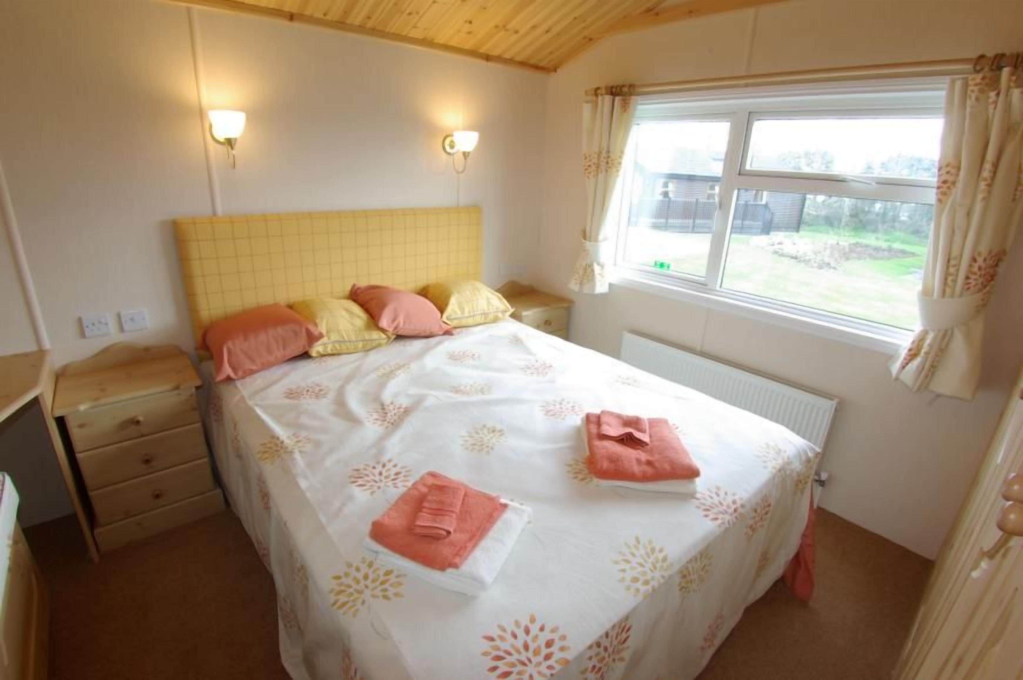 A bedroom with a bed, bedside tables, a window with curtains, and a radiator.