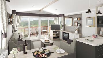 Un salón amplio con un balcón, una mesa de comedor con comida y bebidas, y un televisor montado en la pared.