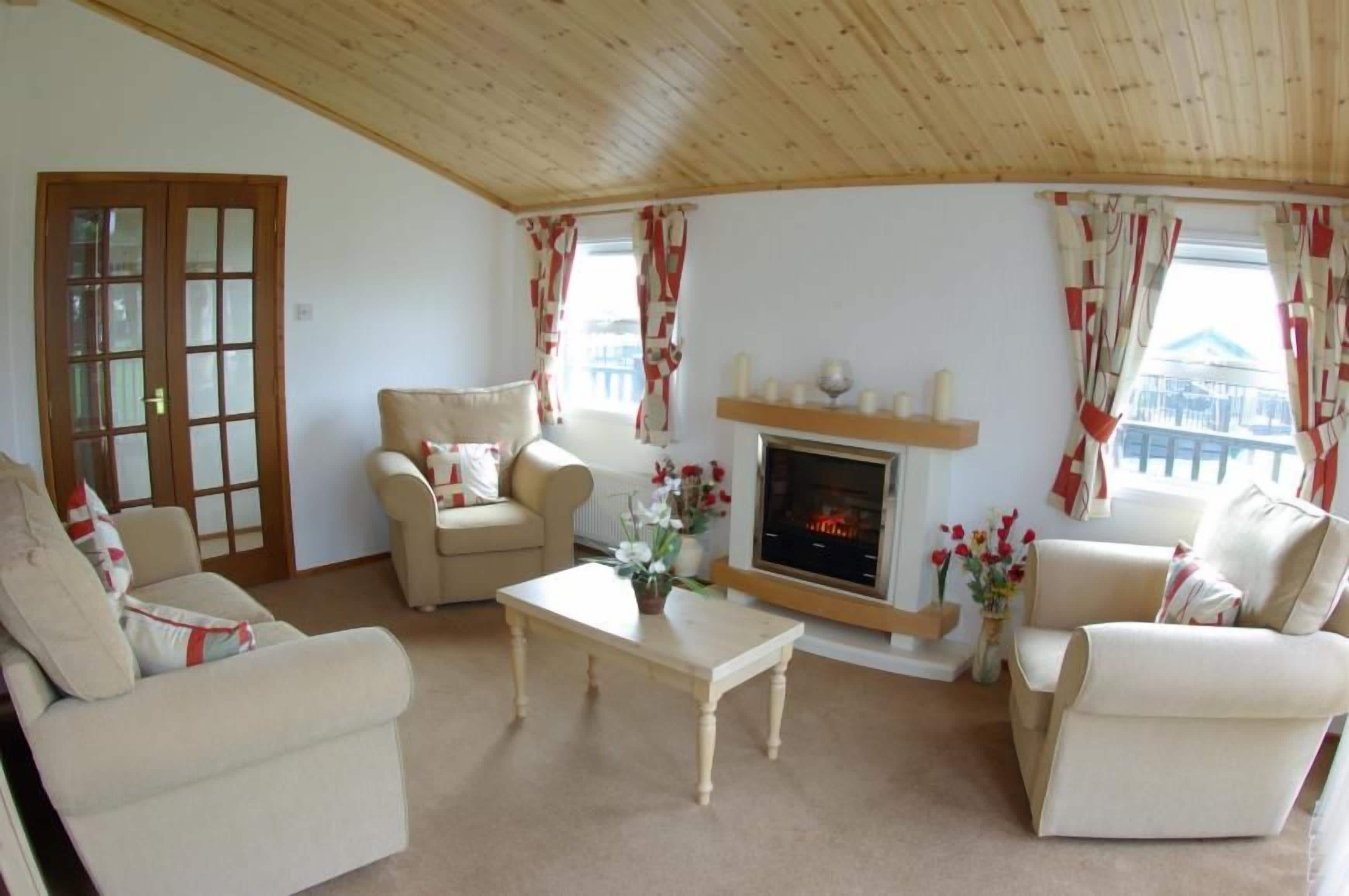 A cozy living room with a fireplace, two sofas, a coffee table, and curtains.