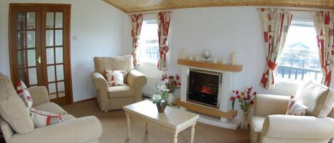 A cozy living room with a fireplace, two sofas, a coffee table, and curtains.