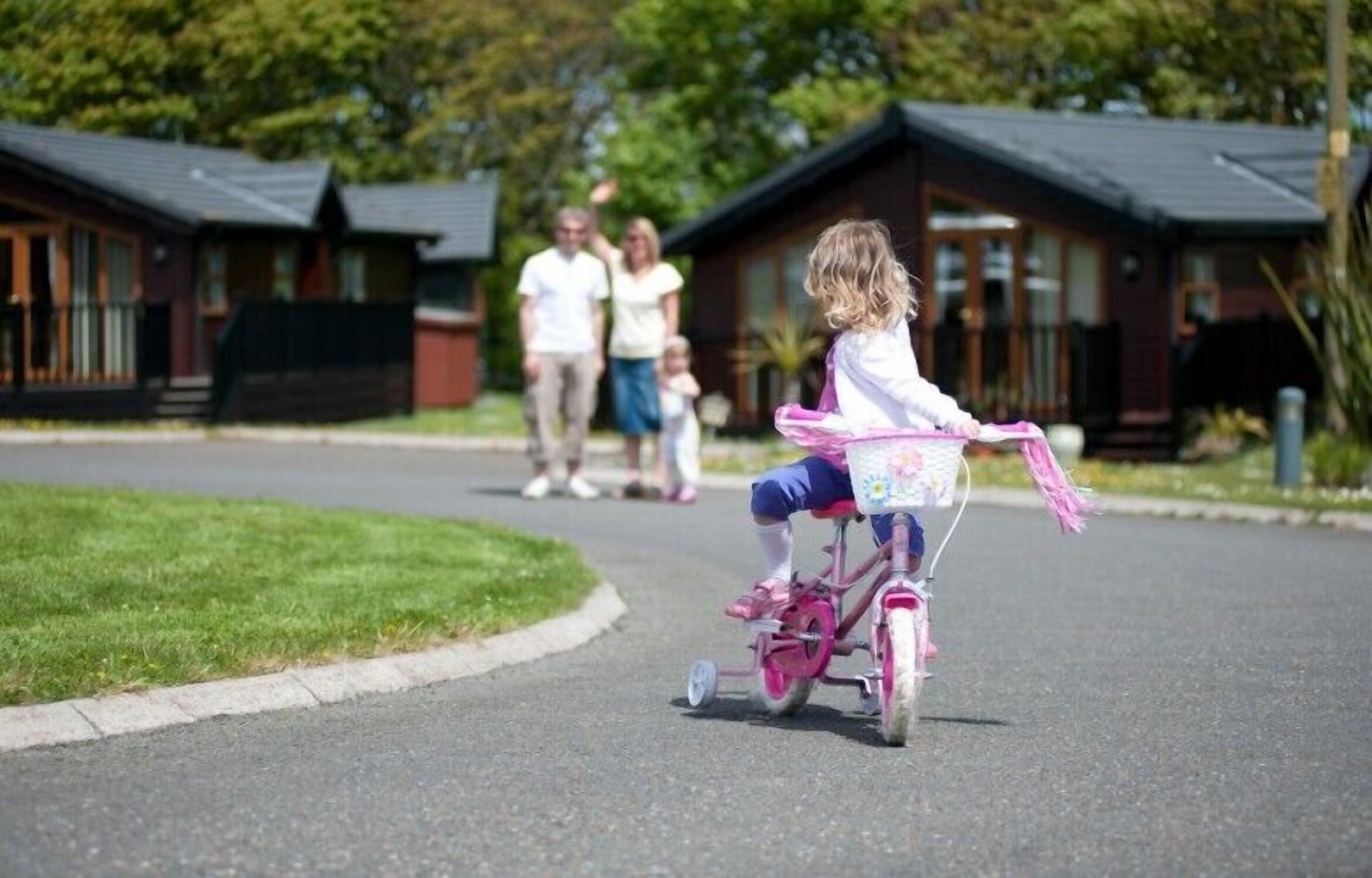 Ett barn som cyklar på en rosa cykel på en asfalterad stig.