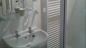 A bathroom with a white sink, a glass shower enclosure, and a towel rack. - Cottage Lea's Country Hotel & Restaurant (Pickering)
