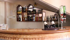 Zona de bar con estantes llenos de botellas y una exhibición de copas de vino.