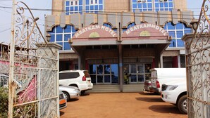 La entrada al Hotel Mbatkam, con un camino de entrada cerrado y coches aparcados.