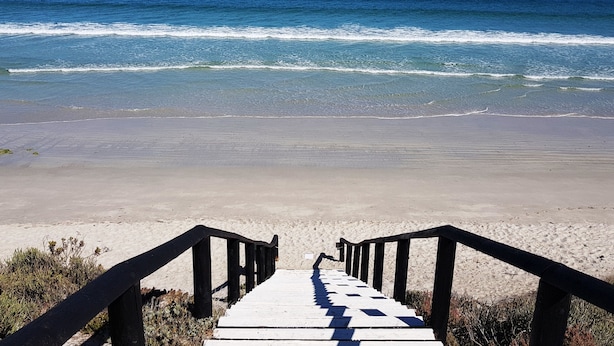 A wooden staircase leading to a beach with clear blue water and distant land. - Seasons of Serenity, Langebaan 8-sleeper (Langebaan)