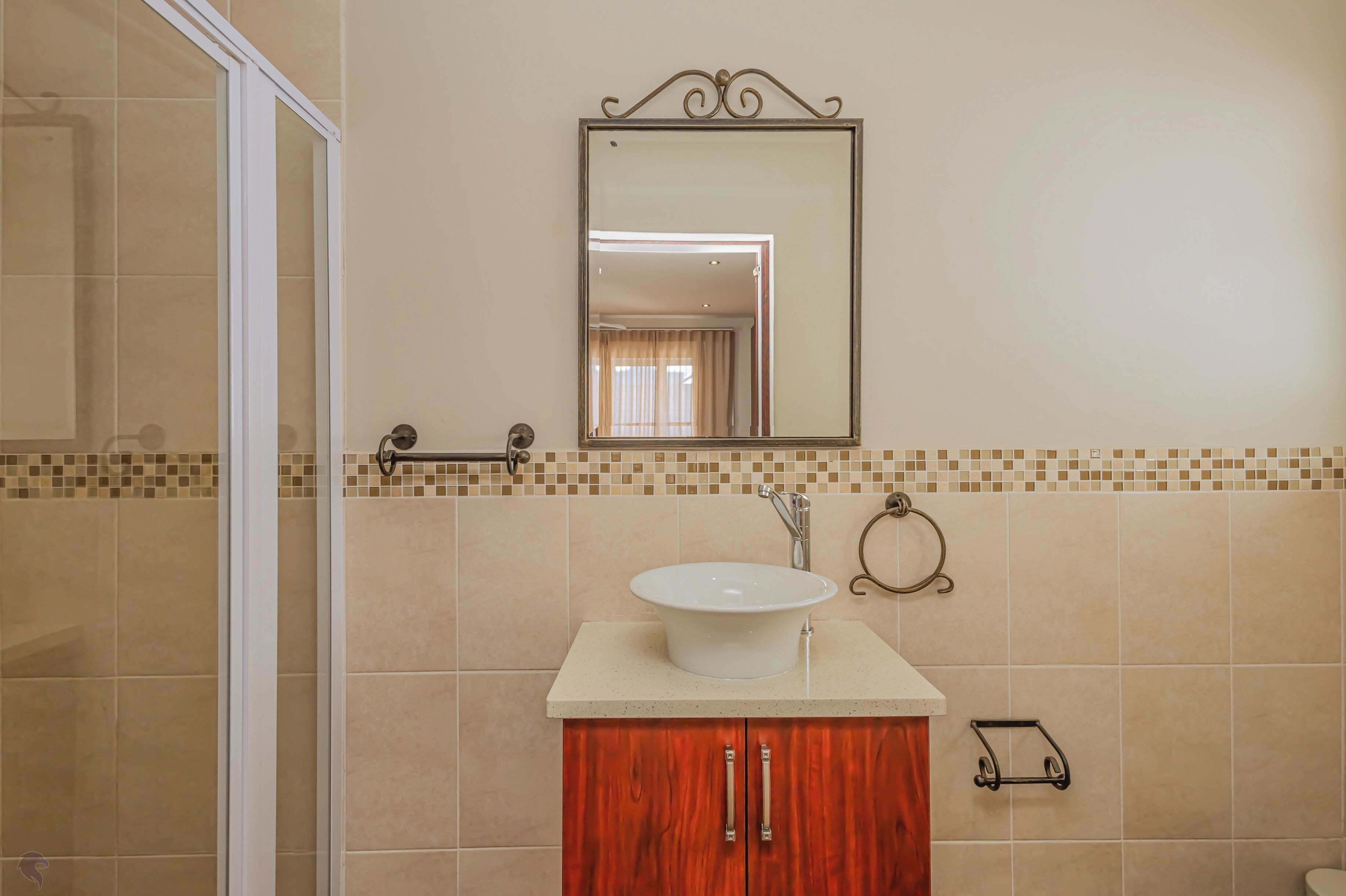 A bathroom with a white sink, wooden cabinet, and a mirror above it.