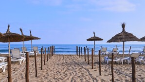 A beach with rows of white lounge chairs and thatched umbrellas, leading to the ocean. - Radisson Blu Resort, Saidia Beach (Saidia)