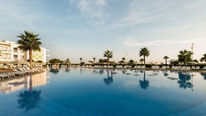 A large, clear swimming pool with lounge chairs and palm trees, surrounded by buildings. - Radisson Blu Resort, Saidia Beach (Saidia)