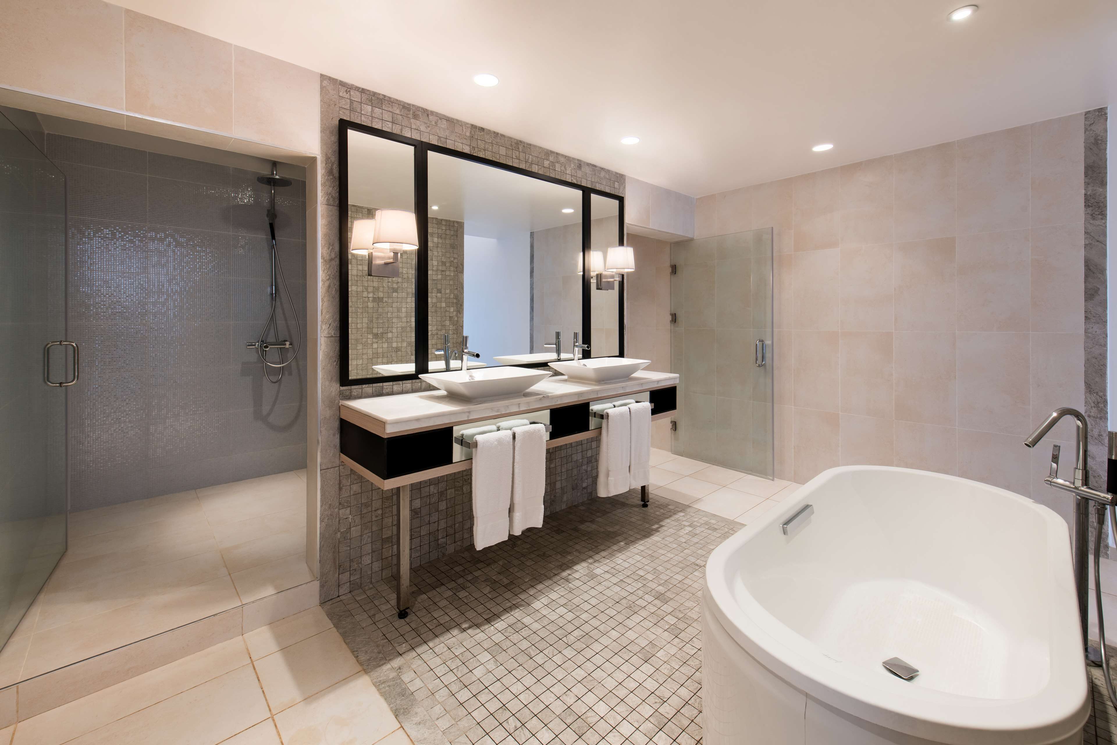 A modern bathroom with a large bathtub, a walk-in shower, and a double sink vanity.