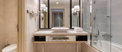 A modern bathroom with a large mirror, a sink, a toilet, and a glass-enclosed shower.
