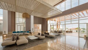 A spacious lobby with modern seating, large windows, and a high ceiling with a geometric pattern. - Radisson Blu Resort, Saidia Beach (Saidia)