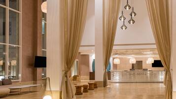 A spacious lobby with a modern design, featuring a reception desk, comfortable seating, and decorative lighting.