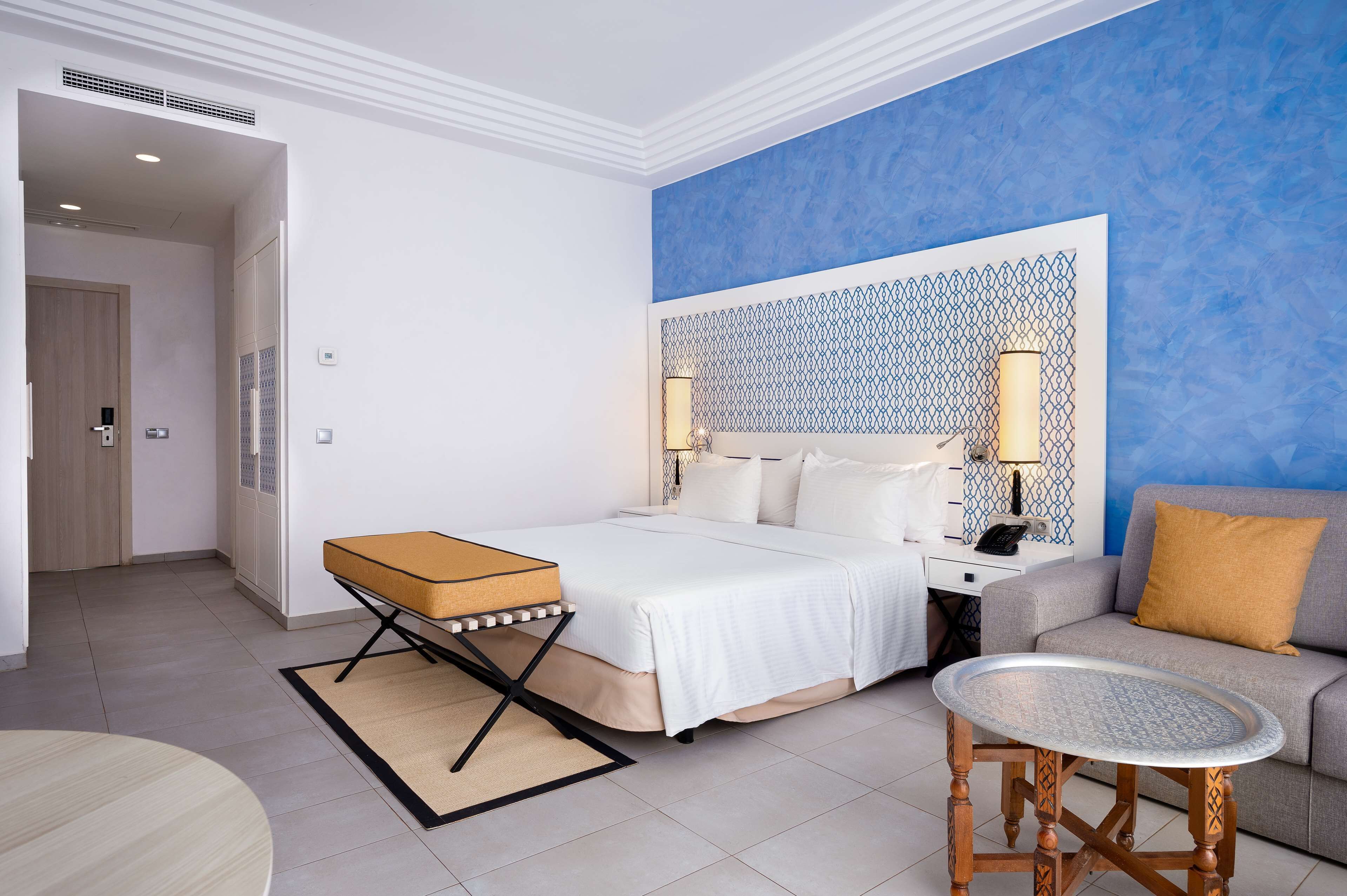 Une chambre d’hôtel comprenant un lit, un canapé, une petite table et une tête de lit décorative.