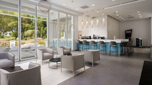 A modern kitchen with a bar area, large windows, and outdoor seating. - Radisson Blu Resort, Saidia Garden (Madagh)