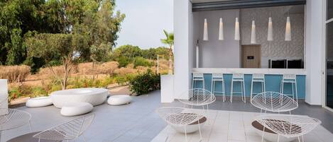 Un patio moderno al aire libre con sillas blancas y una zona de bar.
