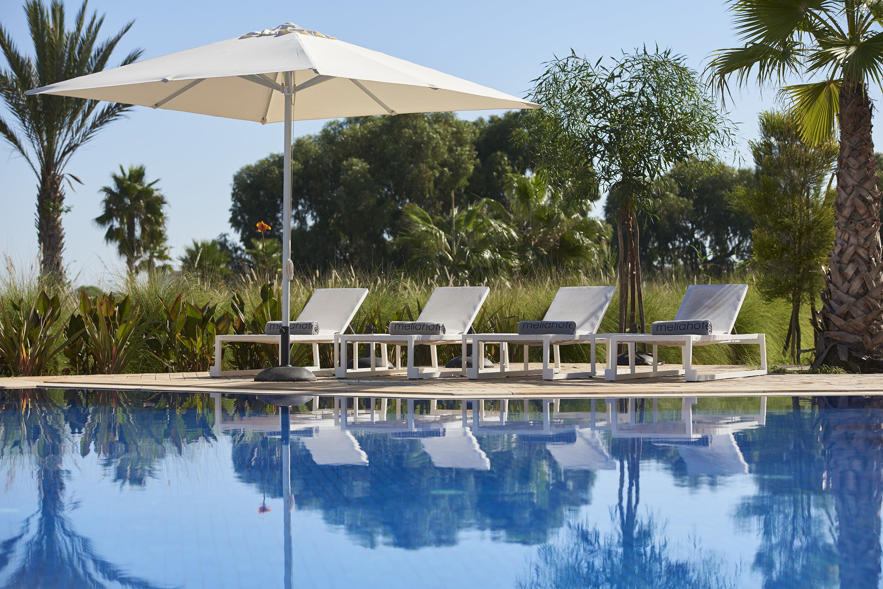 A poolside area with lounge chairs and an umbrella.