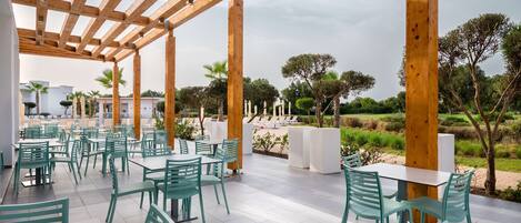 An outdoor patio with wooden pergola, green chairs, and white tables.
