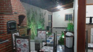 Un comedor con pared de ladrillo, una mesa de vidrio y sillas con tapicería floral.