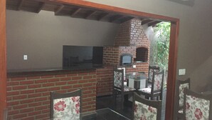 Una sala de estar con chimenea de ladrillo, una mesa de centro de vidrio y sillones tapizados con motivos florales.
