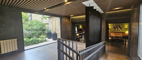 A modern interior with a staircase, a dining area, and a view of greenery outside.