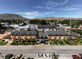 Zona residencial con casas modernas, un estacionamiento y montañas al fondo.