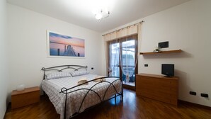 A bedroom with a bed, a dresser, a television on a shelf, and a painting on the wall. - Domus Al Parco Guest House (Fiumicino)