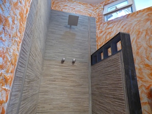 Shower area features a unique, textured wall design and a sliding door with metallic handles.