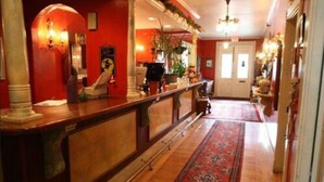 Eine Hotelhalle mit roter Wand, einem Empfangstresen, einem gemusterten Teppich und einer Kristallleuchter.