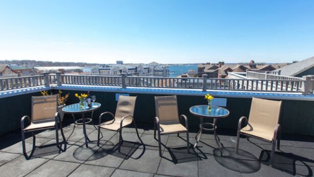 Eine Dachterrasse mit Sitzgelegenheiten im Freien, Blick aufs Meer und einer Brüstung.