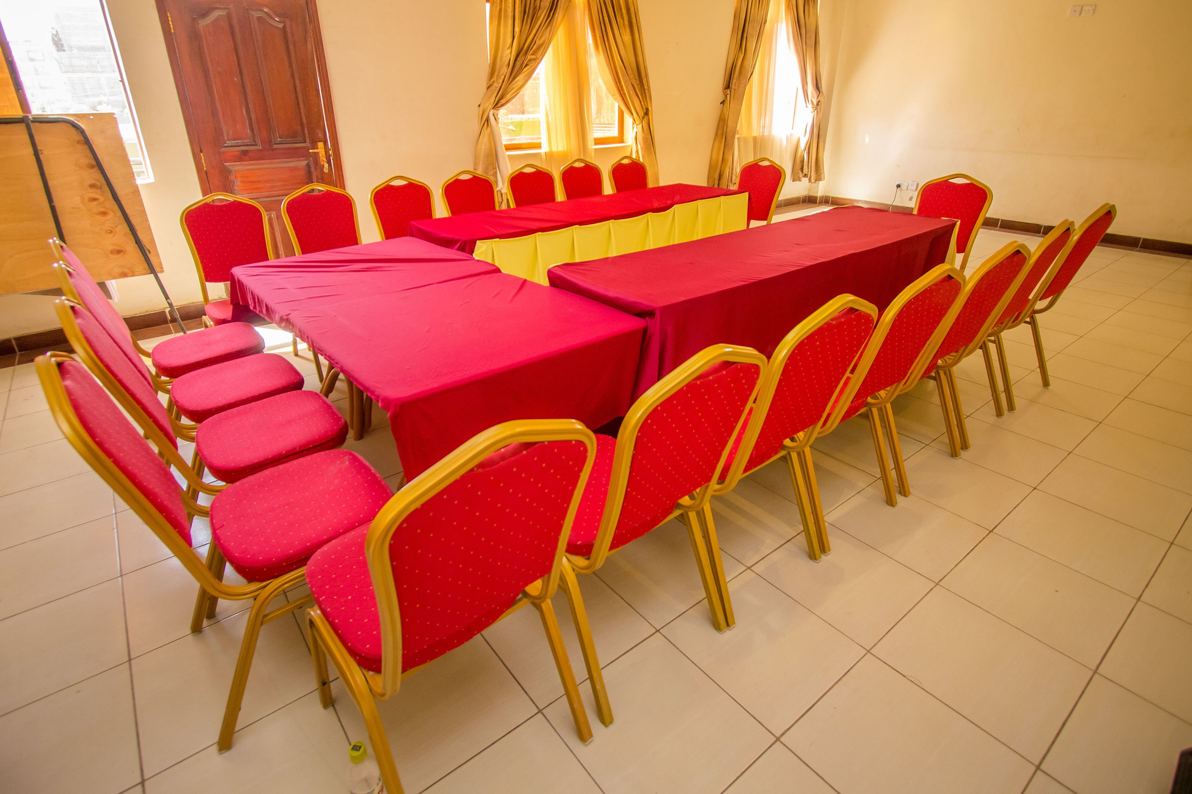 A conference room with a long table and red chairs.
