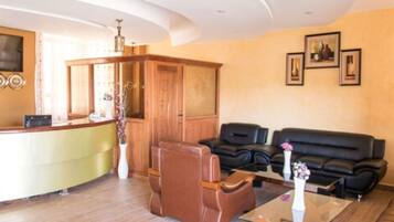 A reception area with a counter, wooden cabinet, leather sofa, and framed pictures on the wall.